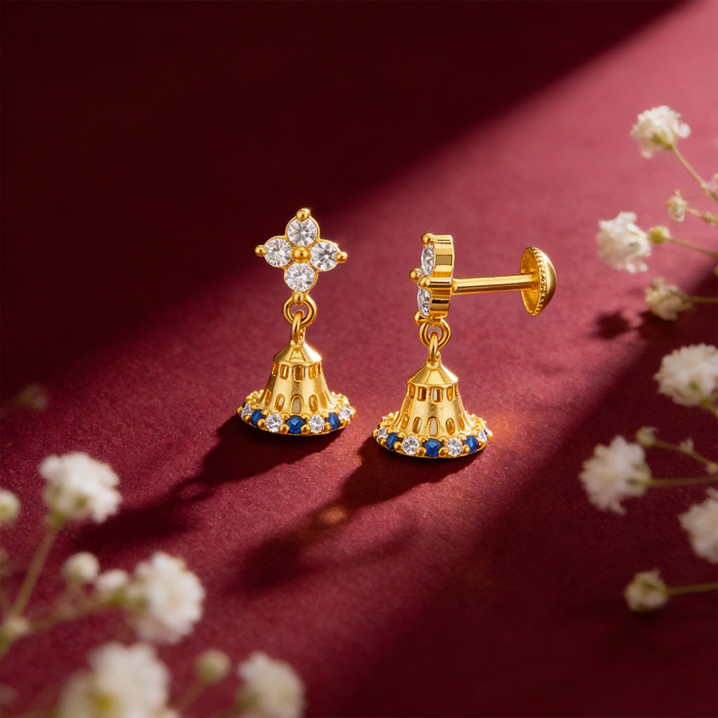 Gold earrings with gemstones on a red background with white flowers