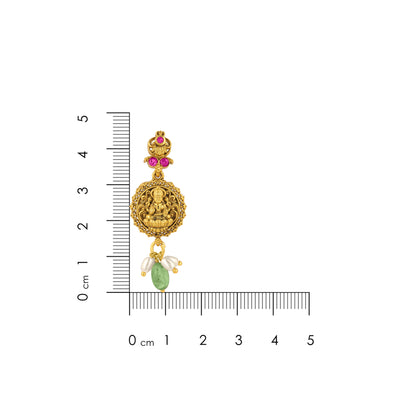 Gold pendant with gemstones on a white background with a ruler for scale.