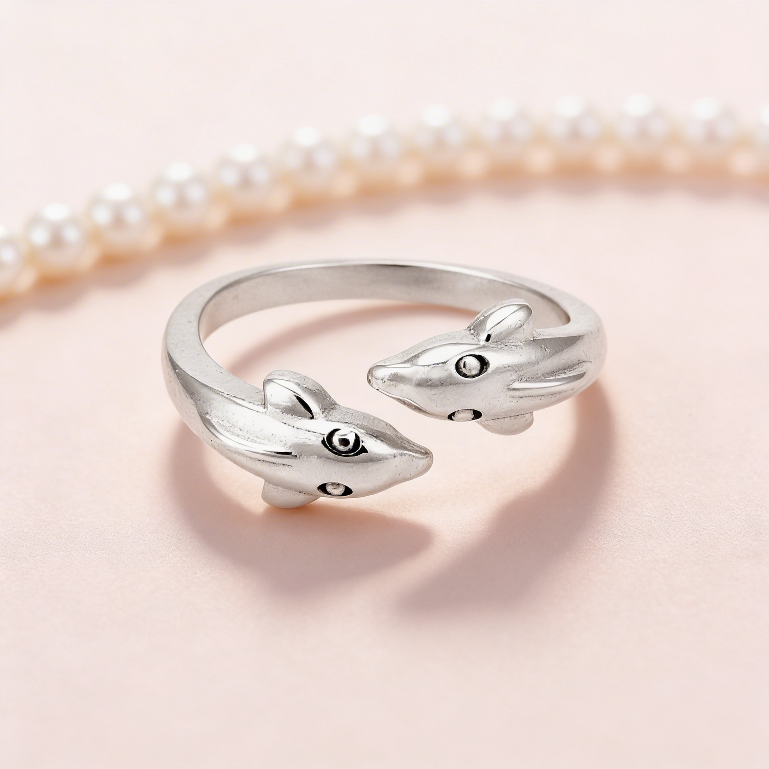 Silver dolphin-shaped ring on a light pink background
