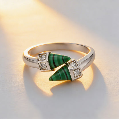 Gold ring with green gemstone and diamonds on a light background