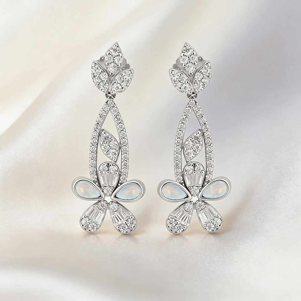 Pair of silver earrings with gemstones on a light background