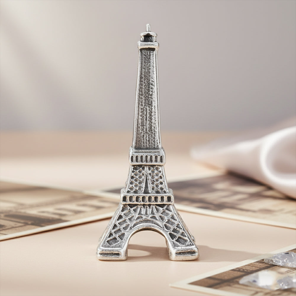 Silver Eiffel Tower model on a textured surface with a neutral background