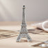 Silver Eiffel Tower model on a textured surface with a neutral background