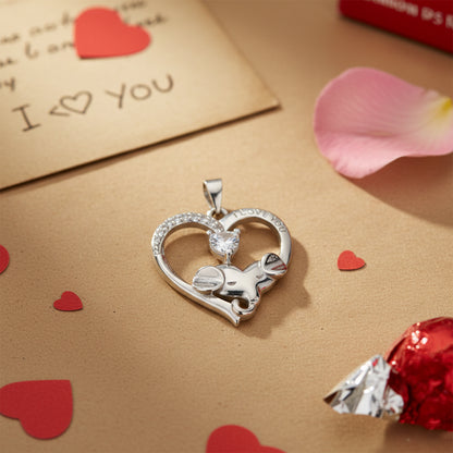 Silver heart-shaped pendant with a small animal figure on a beige surface with heart decorations.