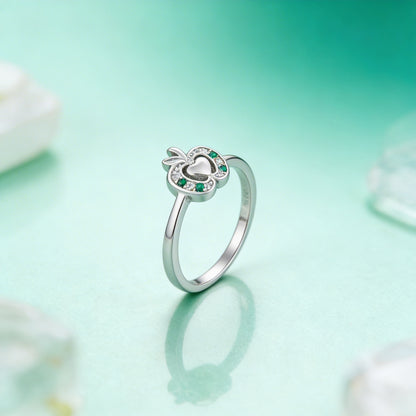 Silver ring with green gemstones on a light green background