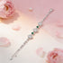 Silver bracelet with green gemstones on a soft pink floral background