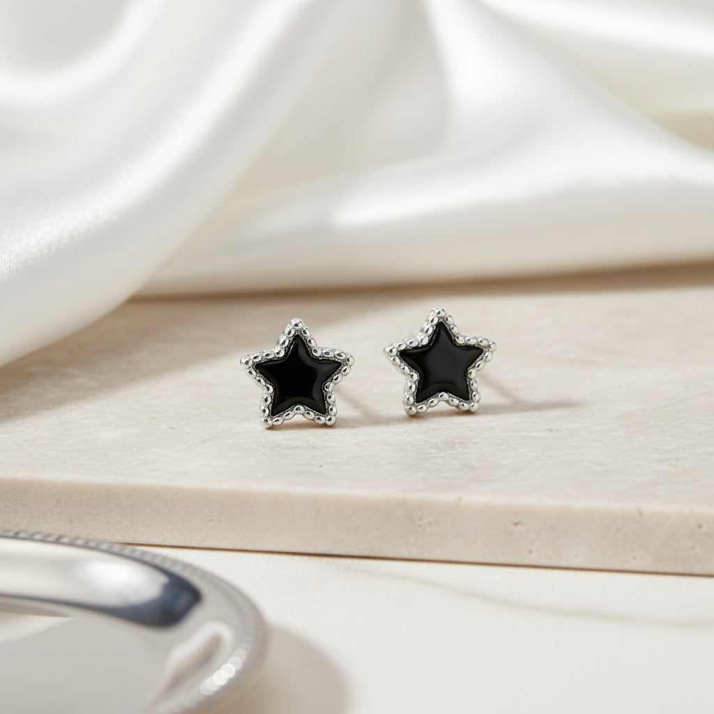 Star-shaped earrings with black stones on a light wooden surface