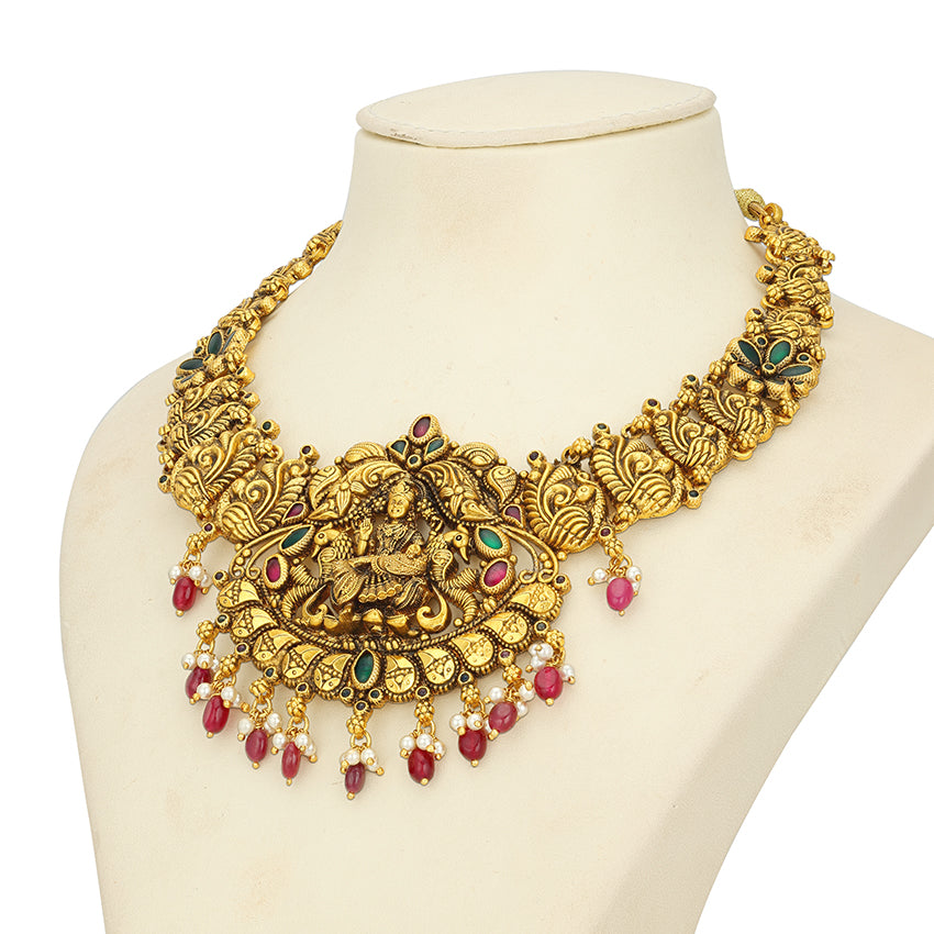 Ornate gold necklace with red and green accents on a mannequin bust.
