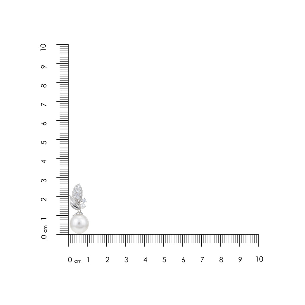 Earring with a pearl and leaf design next to a ruler for scale on a white background