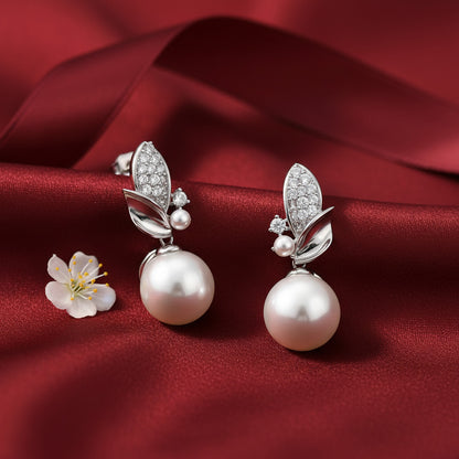 Pearl earrings with silver leaves on a red satin background