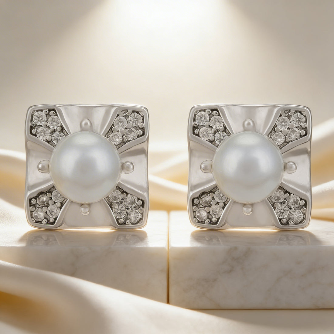 Pair of pearl earrings with silver and diamond accents on a marble surface