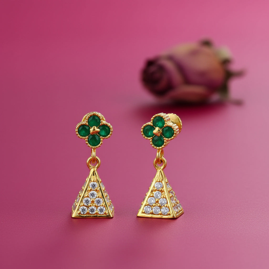 Gold earrings with green and clear gemstones on a pink background