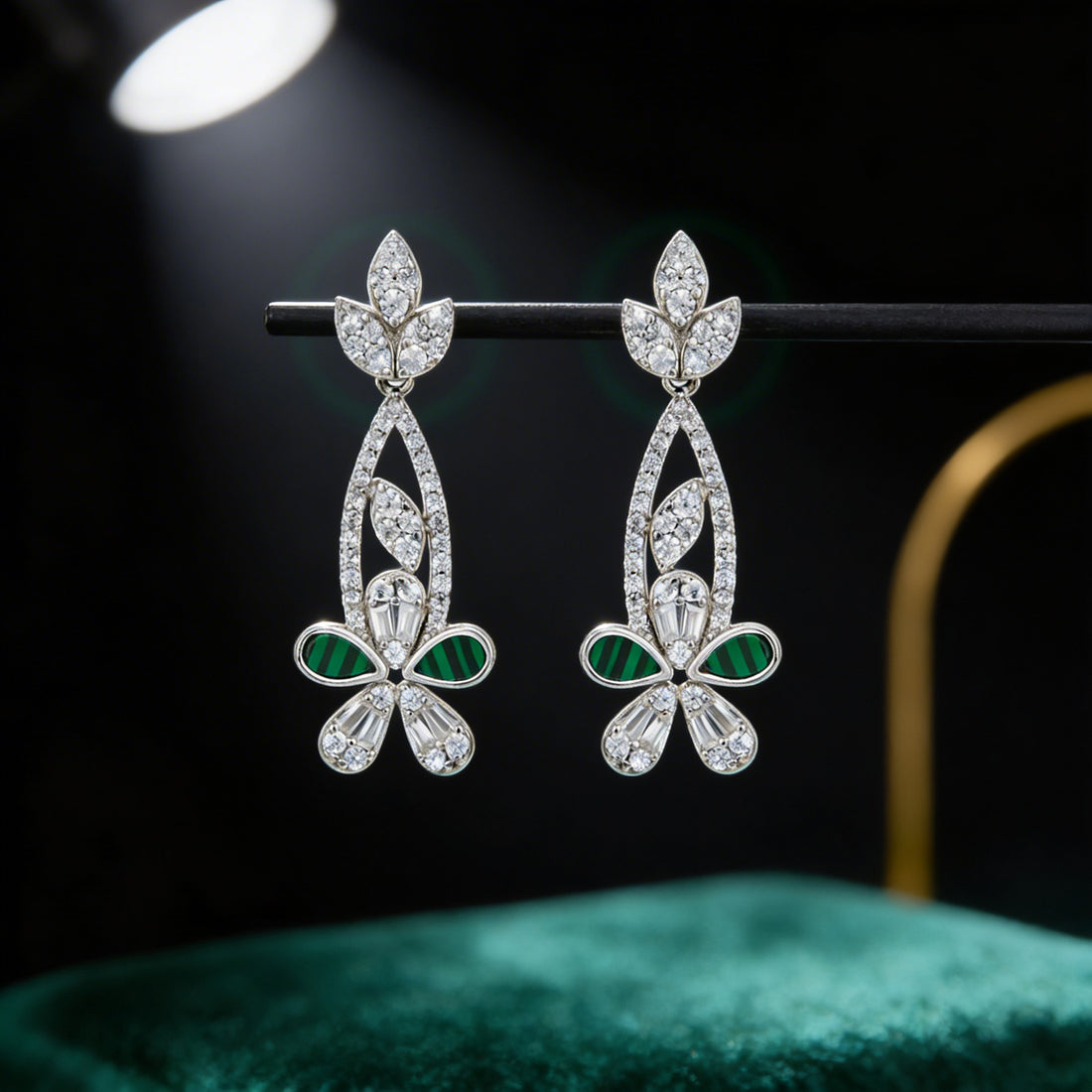 Pair of silver earrings with green gemstones on a dark background
