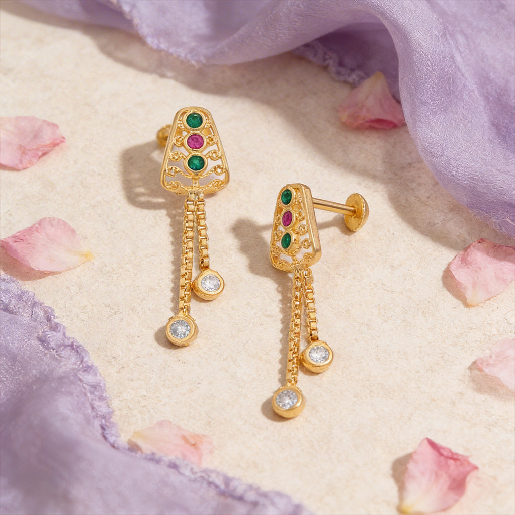 Gold earrings with gemstones on a soft fabric background