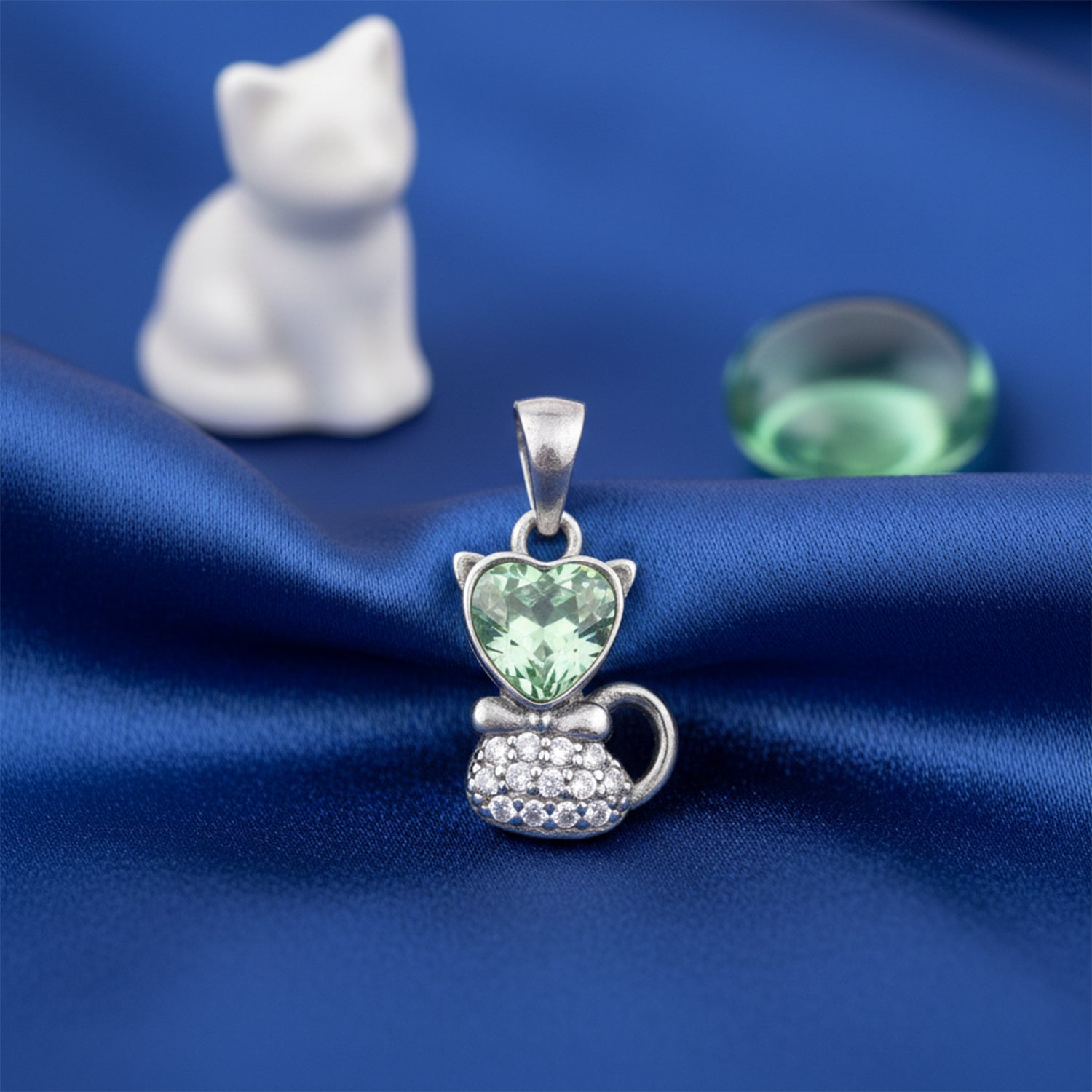 Cat-shaped pendant with green gemstone on blue fabric
