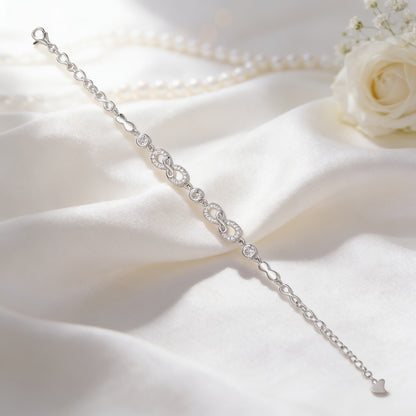 Silver bracelet on a white fabric background with a white rose.