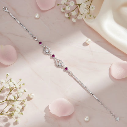 Silver bracelet with heart-shaped charms on a pink surface with flowers