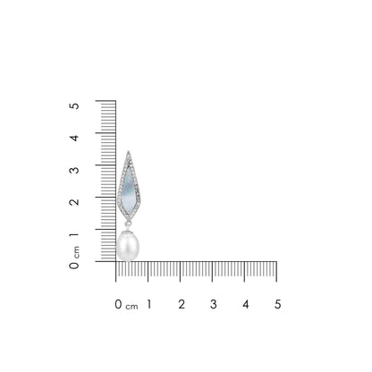 Jewelry earring with pearl and gemstones next to a ruler for scale on a white background