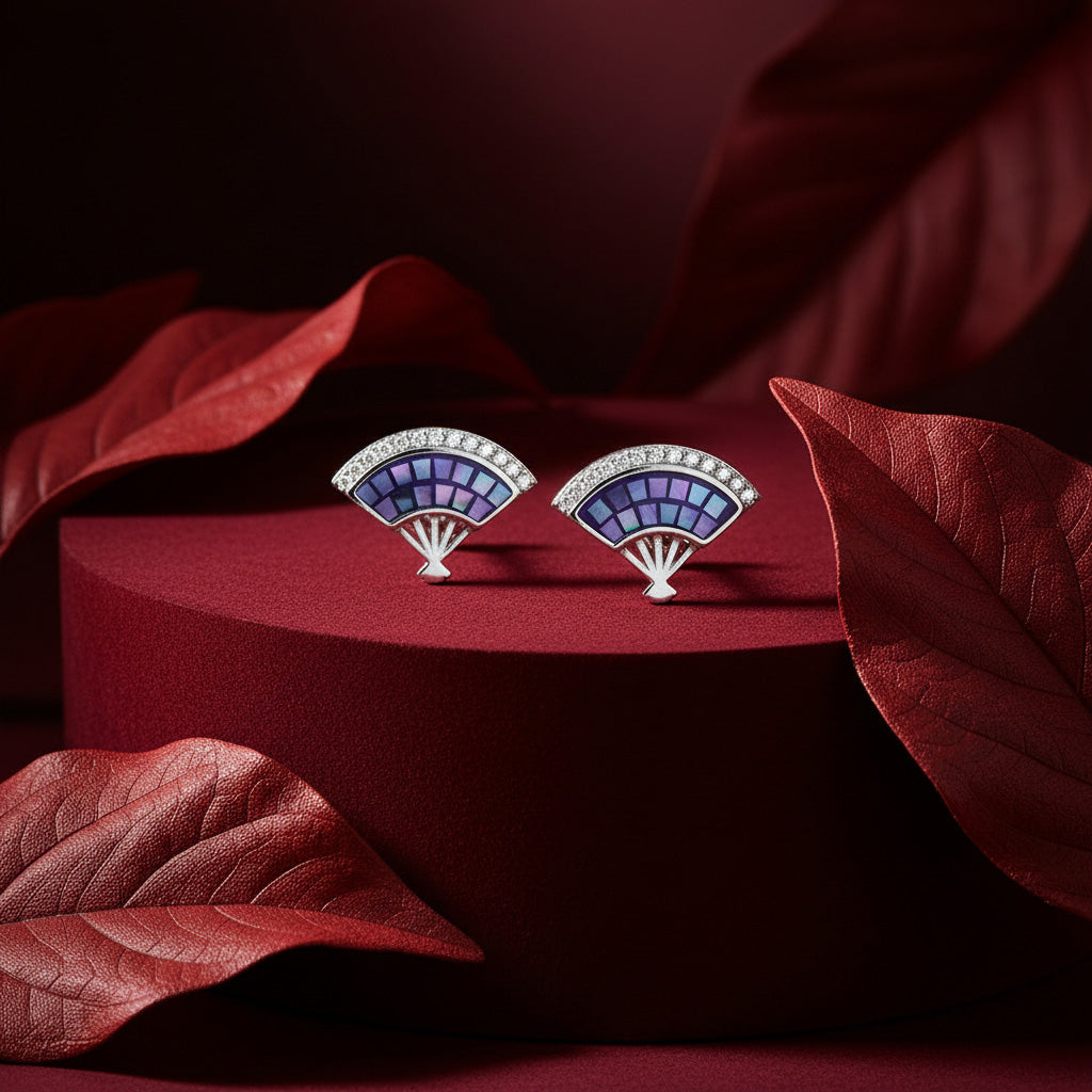 Fan-shaped earrings with purple and blue design on a red stand with red leaves.