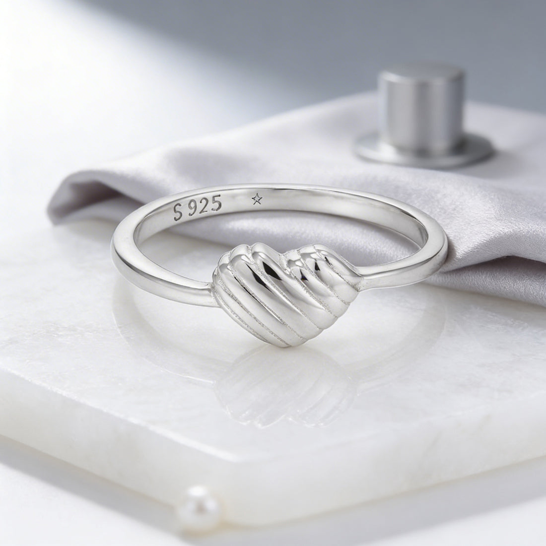 Silver ring with wave design on a white surface