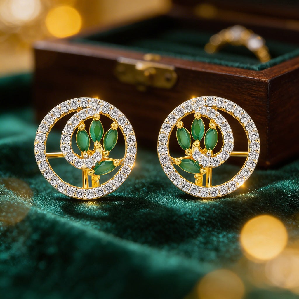 Pair of gold and green earrings on a green fabric background