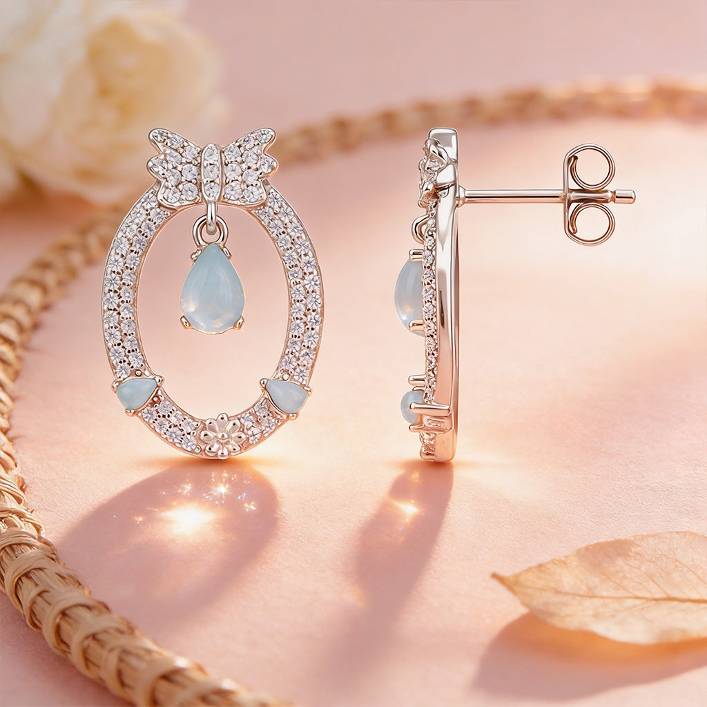 Rose gold earrings with gemstones on a soft pink background