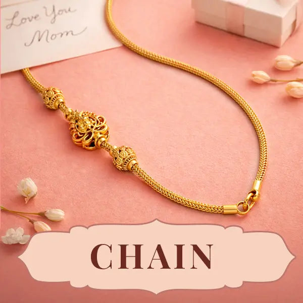 Gold chain necklace on a pink surface with decorative elements