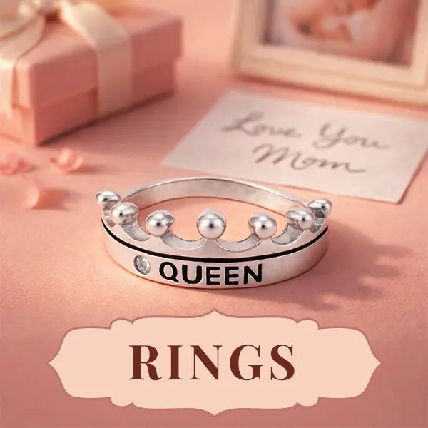 Silver ring with 'QUEEN' engraving on a pink surface with 'Love You Mom' card
