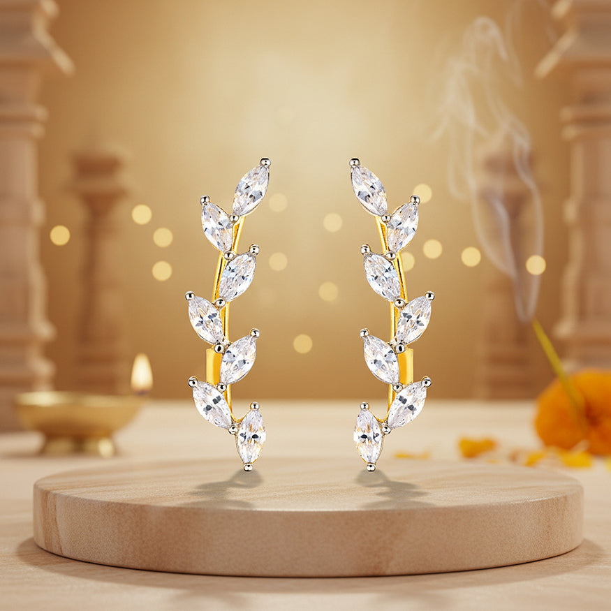 Gold and diamond earrings on a wooden platform with a warm background