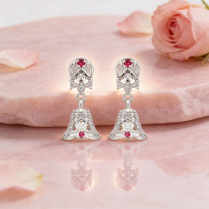 Silver earrings with red gemstones on a pink floral background