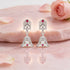 Silver earrings with red gemstones on a pink floral background