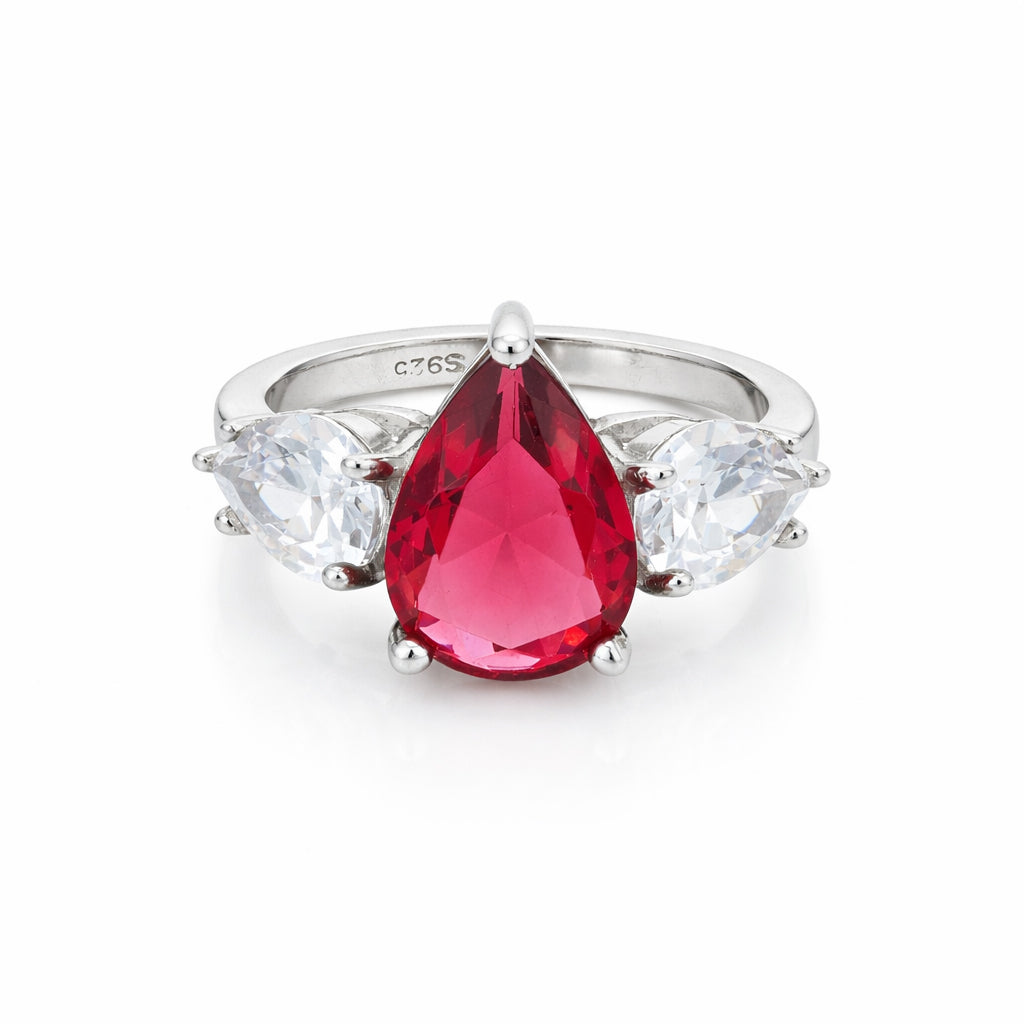 Silver ring with a red teardrop-shaped gemstone and clear side stones on a white background