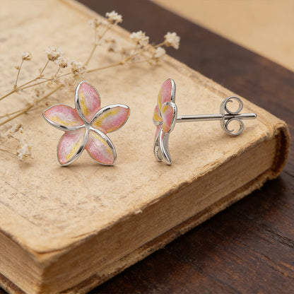 Flower-shaped earrings on an old book with dried flowers.