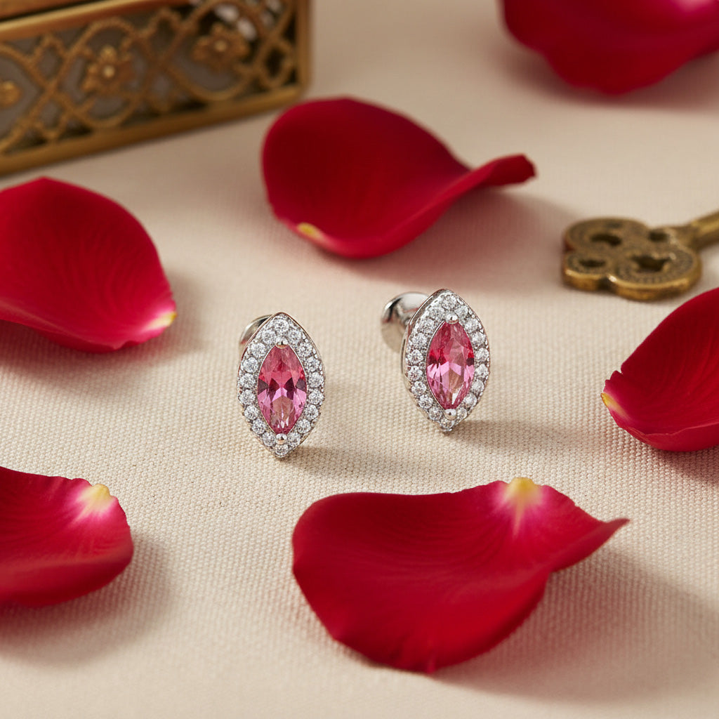 Pink gemstone earrings with silver setting on red rose petals