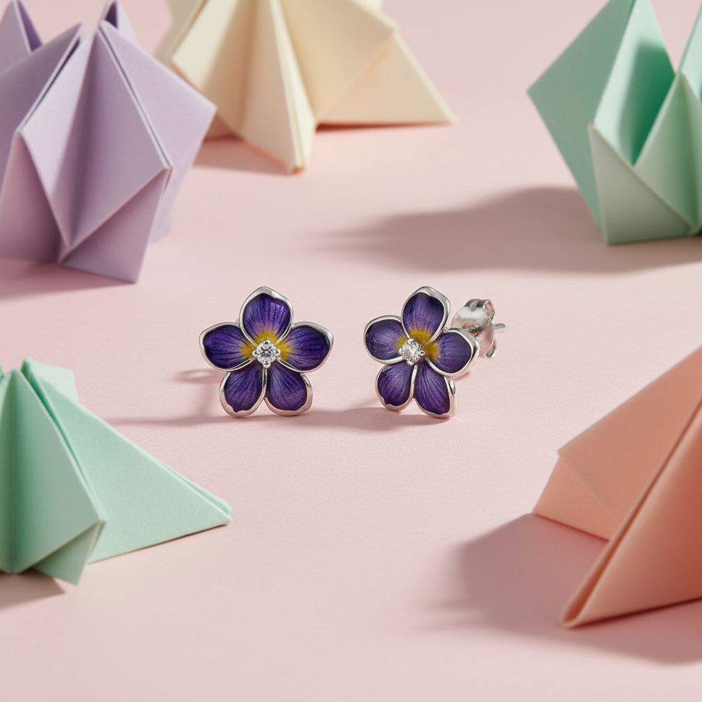 Purple flower-shaped earrings on a pink background with origami decorations