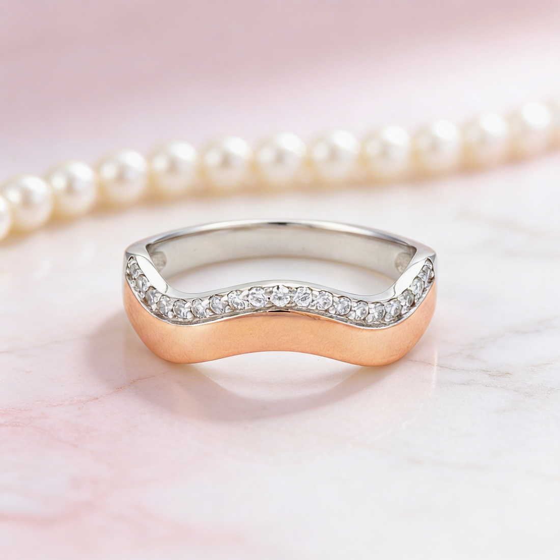 Gold and silver ring with small diamonds on a pink background