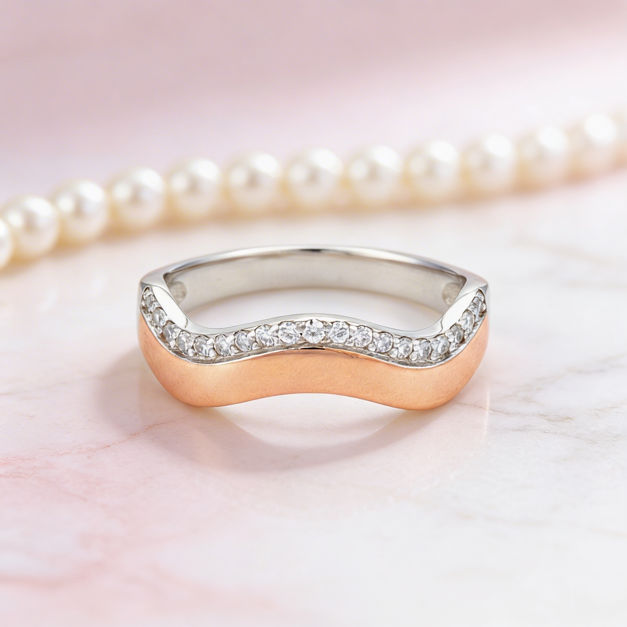 Gold and silver ring with small diamonds on a pink background