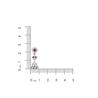 Jewelry earring with embedded gemstones next to a ruler for scale on a white background
