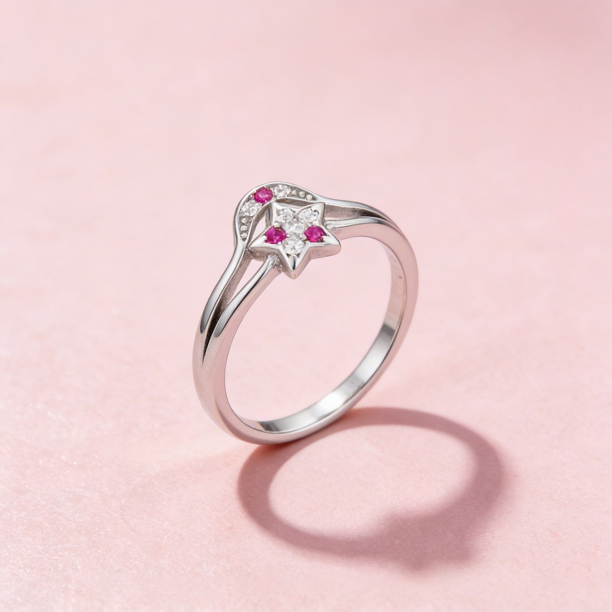 Silver ring with pink gemstones on a pink background