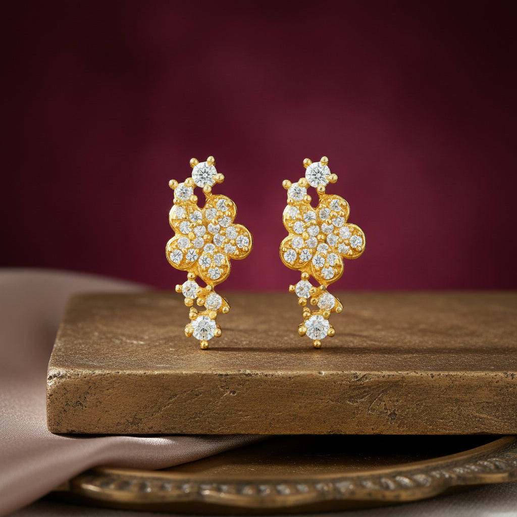 Gold earrings with diamonds on a wooden surface against a purple background