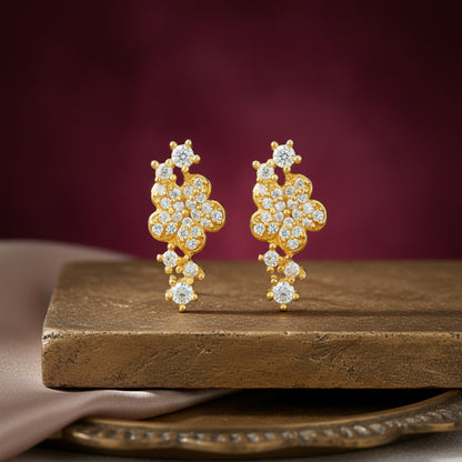 Gold earrings with diamonds on a wooden surface against a purple background