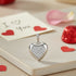 Heart-shaped silver pendant with clear stones on a romantic setting with &