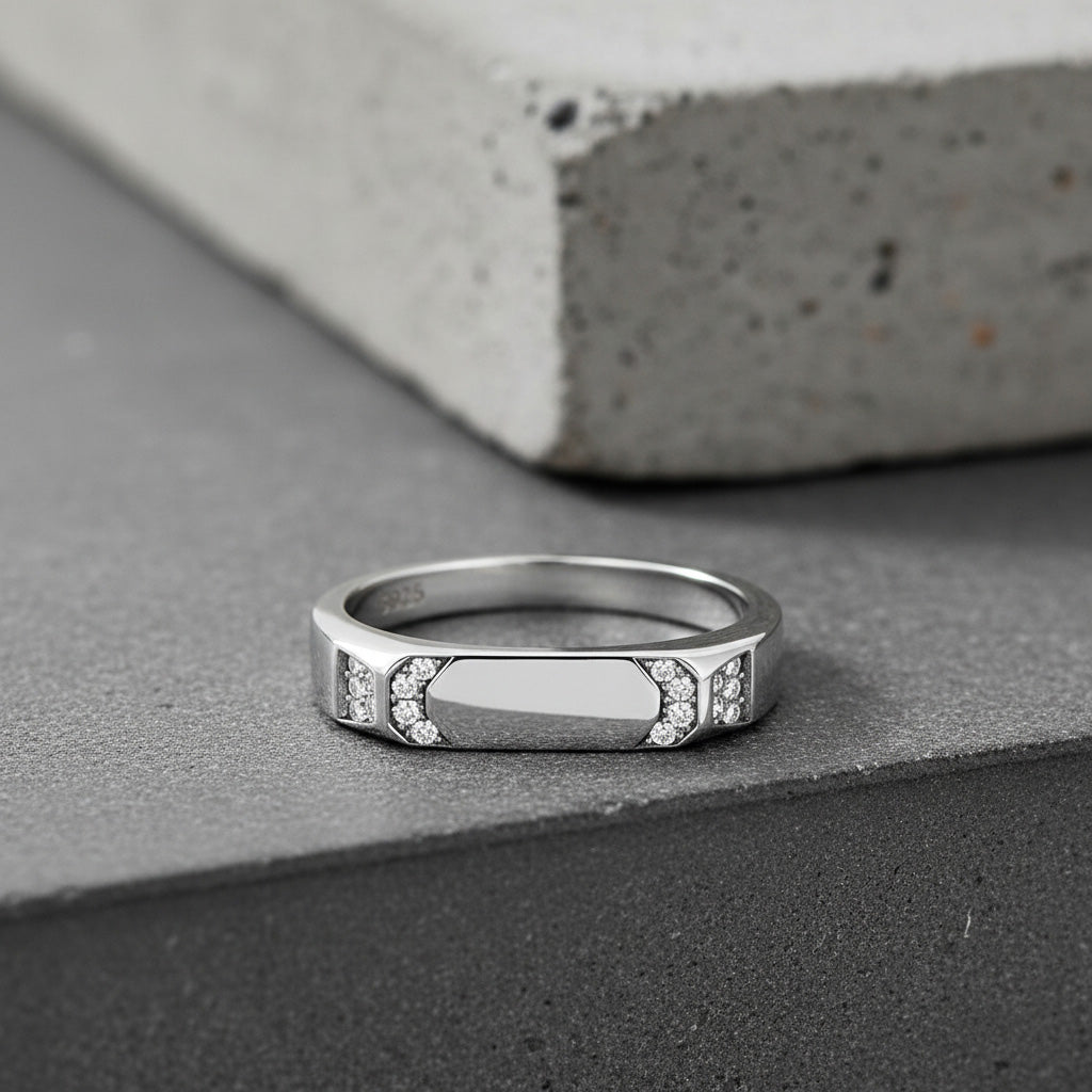 Silver ring with embedded stones on a gray surface