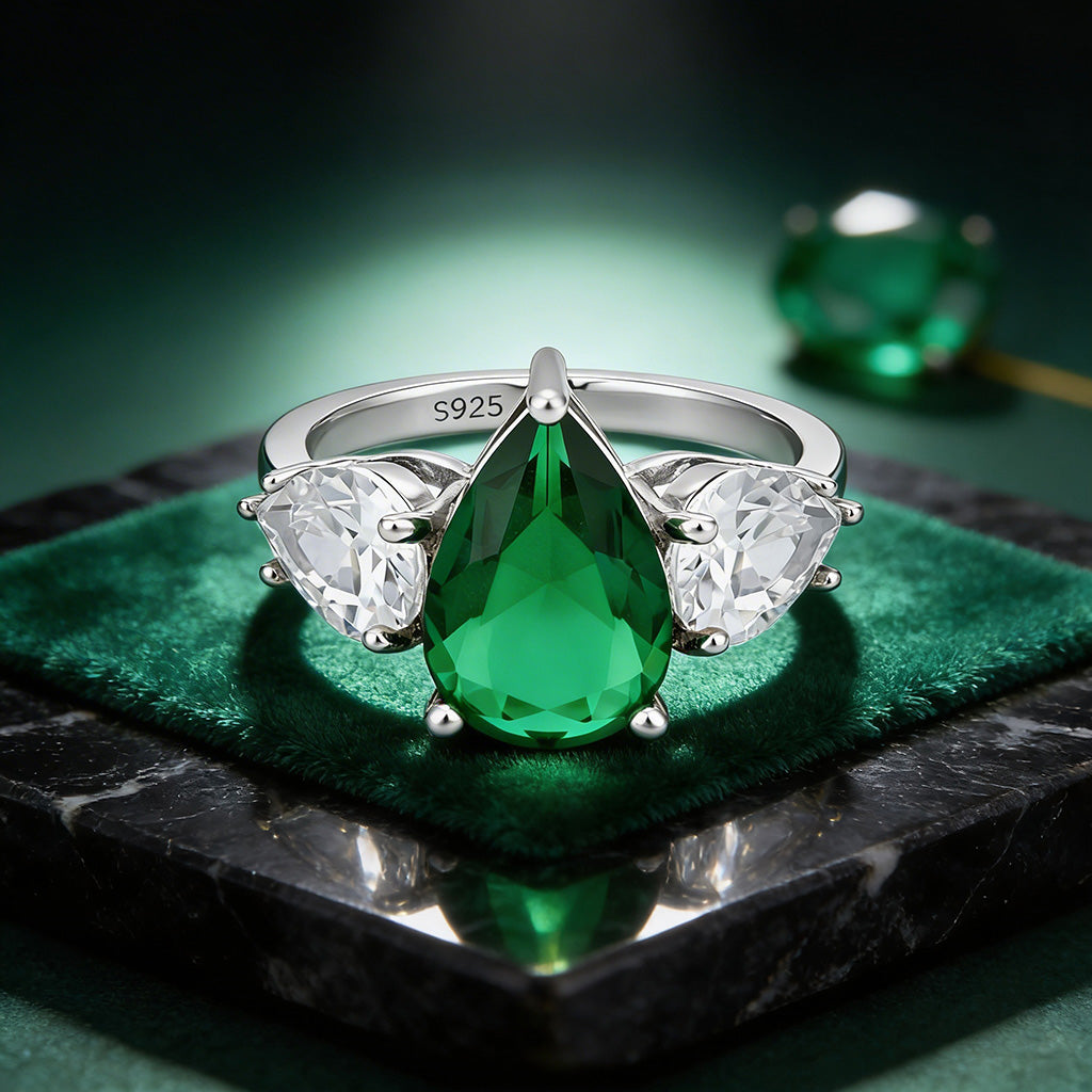Silver ring with a green teardrop gemstone on a dark surface