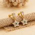 Gold earrings with star designs and gemstones on a textured beige surface