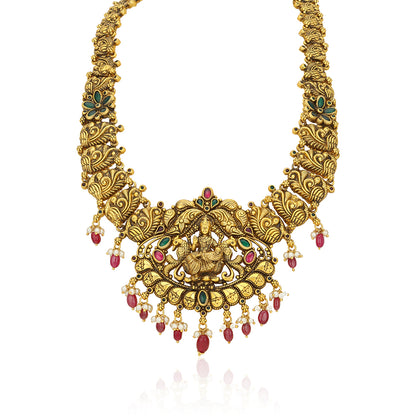 Gold necklace with intricate designs and red and green gemstones on a white background
