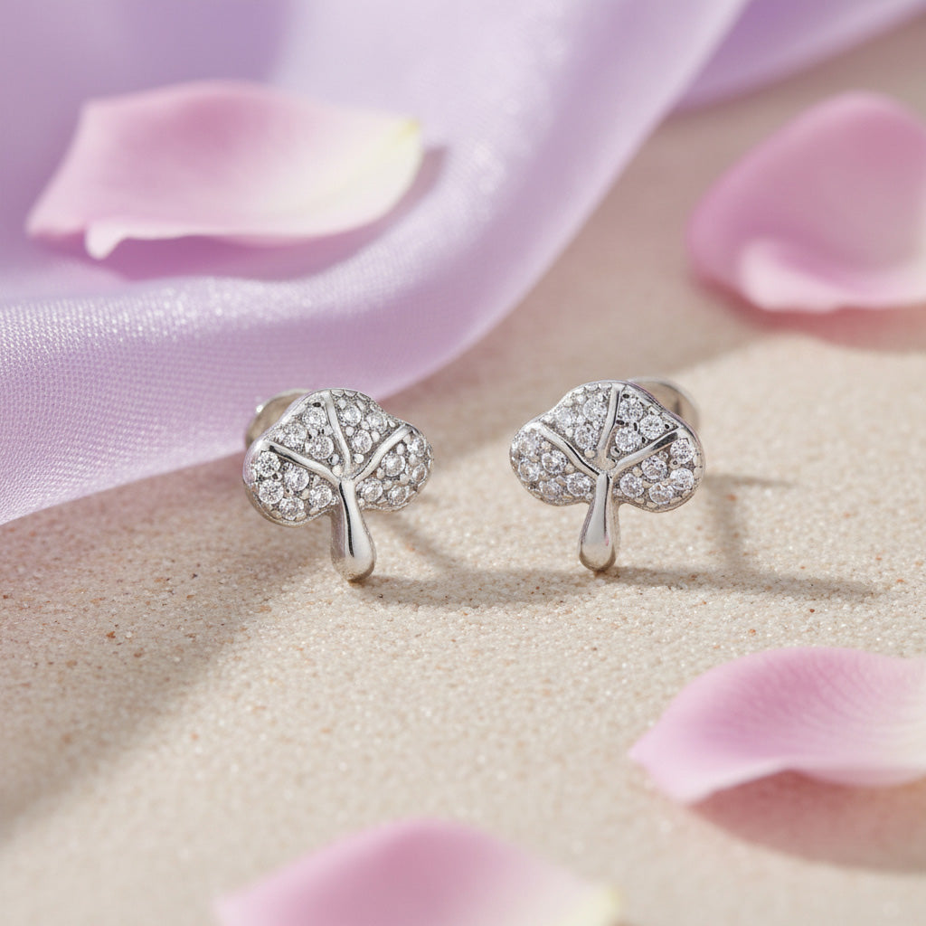 Silver earrings with leaf design on a pink fabric background